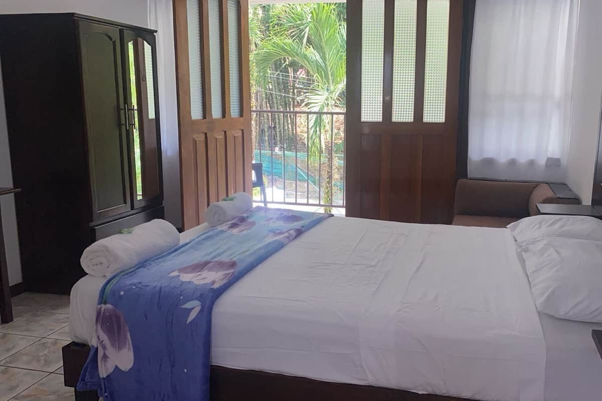 Un dormitorio con cama, un armario de madera y vistas a un área exterior cercada.