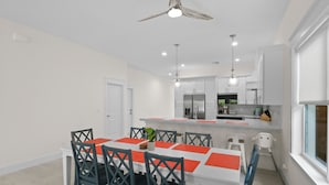 A modern kitchen with white cabinets, a central island, and a dining area with a table and chairs.