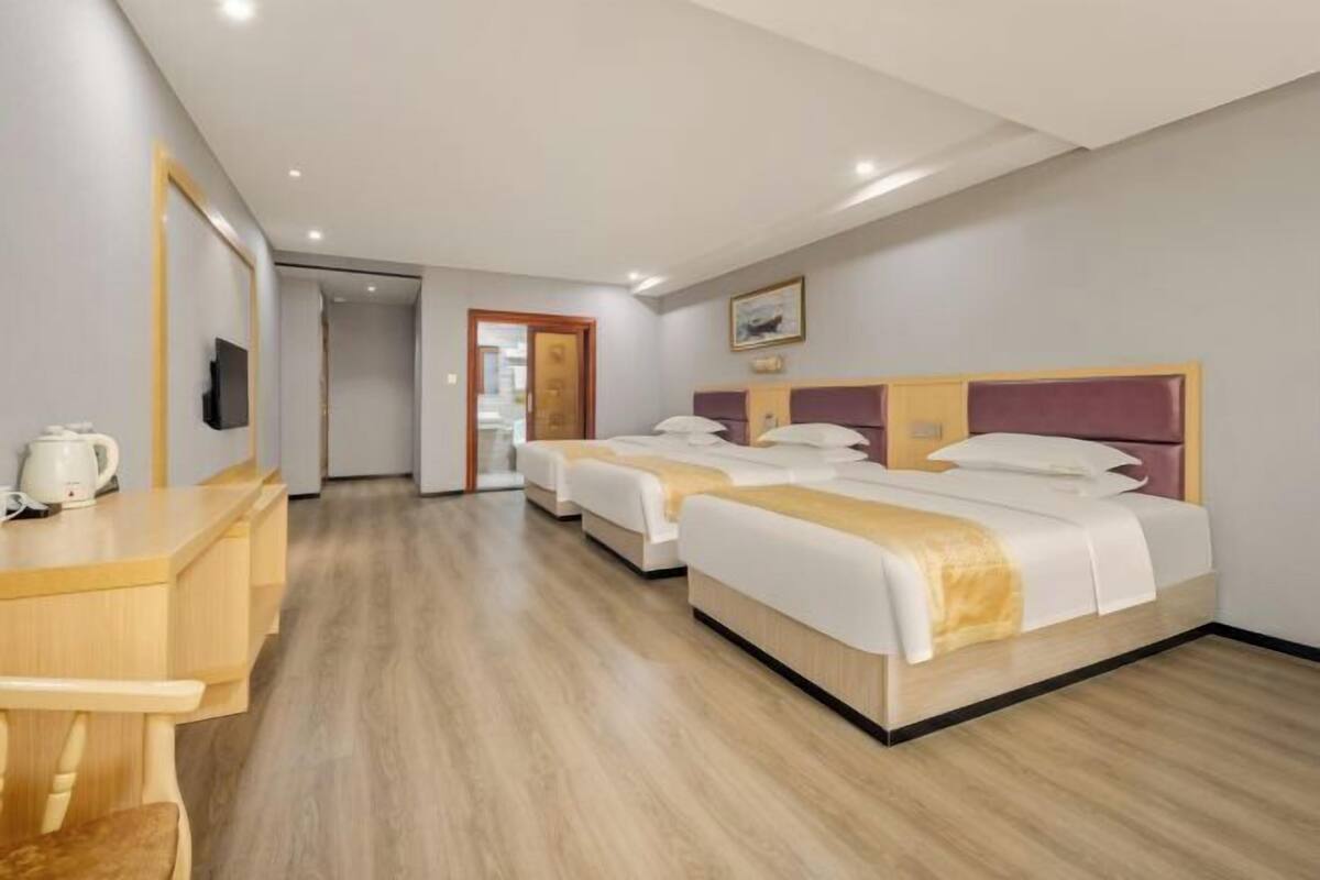 Een hotelkamer met twee enkele bedden, een houten bureau met een stoel, en een televisie aan de muur.