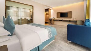 Una habitación de hotel con una cama, un sofá, un televisor y un escritorio.