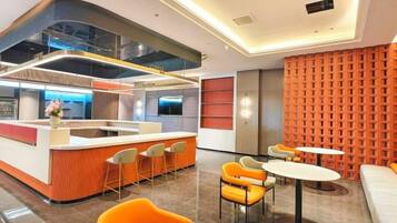 A modern hotel lobby with a central bar area, seating arrangements, and a patterned wall.