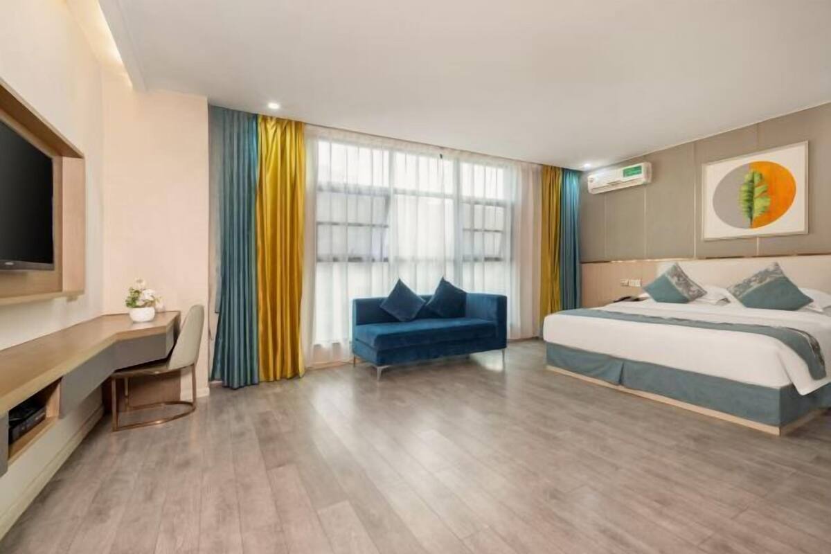 Een moderne hotelkamer met een bed, een bureau, een bank en een televisie.
