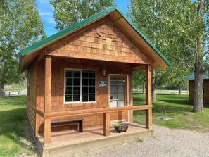 A wooden cabin with a green roof, a front porch, and a sign that reads "The Ranch House." - Longhorn Cabin At Mountain River Ranch (Ririe)