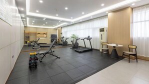 Ett modernt hotellgym med träningsutrustning, löpband och en matplats.
