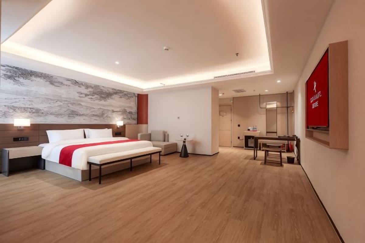 A modern hotel room with a large bed, bedside tables, a desk, and a mirror.