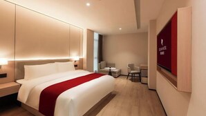 Ett modernt hotellrum med en stor säng, sängbord, ett skrivbord och en stol.
