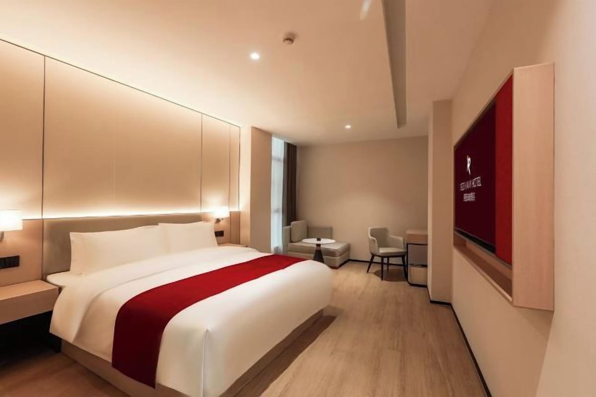 A modern hotel room with a large bed, bedside tables, a desk, and a chair.