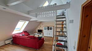 A loft-style room with a red sofa, wooden flooring, a white staircase, and a skylight. - A millside dream, stylish, right next to the historic mill, not far from the harbor... (Ditzum)