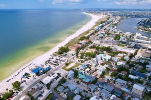 Une vue aérienne d’une ville côtière avec une plage, des routes et des bâtiments.