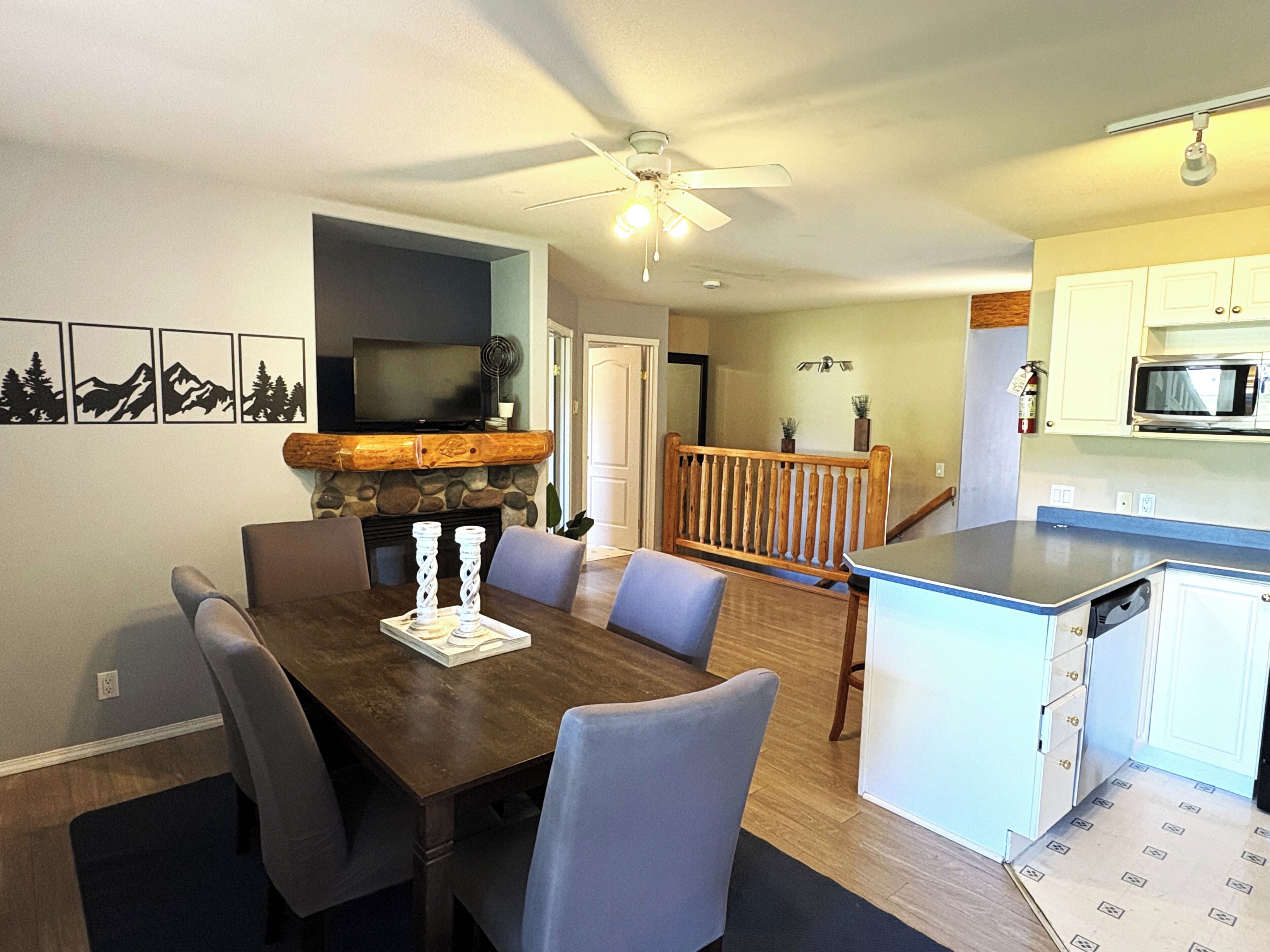 Un comedor con una mesa y sillas de madera, una chimenea y un televisor en la pared.