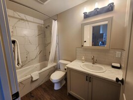 Un baño con bañera, inodoro y tocador con espejo.