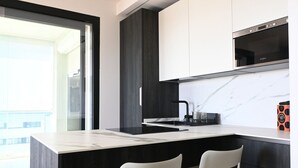 A modern kitchen with a large island, dark cabinetry, and a built-in microwave.