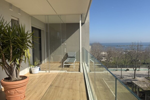 Un balcón con vista al mar, una planta en maceta y una silla.