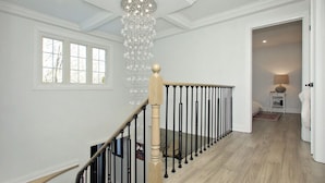 Eine Treppe mit hölzernem Geländer und schwarzen Spindeln, die zu einem Raum mit einer Lampe und einem Teppich führt.