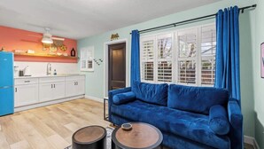 A compact living space with a kitchenette, a blue sofa, and a dining area.