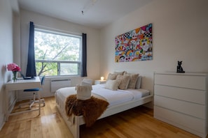Relax in a serene bedroom with a plush bed, a dresser, and a vibrant abstract painting.