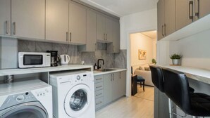 A modern kitchen with built-in appliances, a washing machine, and a dining area with a sofa and chairs.