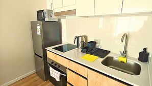 Una cocina funcional con refrigerador, estufa, pileta y alacenas de madera.