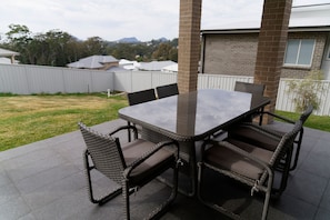 An outdoor patio with a rectangular table and six wicker chairs. - Seabreeze at Corlette (Corlette)