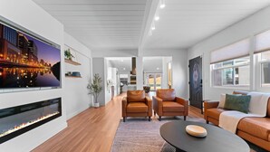 Een moderne woonkamer met een open haard, leren banken, een salontafel en een grote televisie.