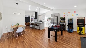 Een moderne keuken met een centraal eiland, een eethoek met een tafel en stoelen, en een tafelvoetbaltafel.