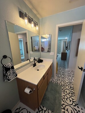 A bathroom with a double sink, a large mirror, and a patterned floor.