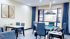 Una habitación de hotel moderna con mesa de billar, asientos cómodos y ventanas amplias con vistas a la ciudad.
