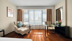 Habitación de hotel moderna con un ventanal grande, un sofá, una mesita redonda pequeña y una mesa de centro de vidrio.