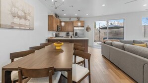 Una cuina moderna amb armaris de fusta, una illa central i una zona de menjador amb taula i cadires de fusta.