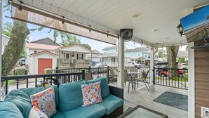 A covered outdoor area with a sofa, chairs, and a table. - Cottage in Ocean Lakes w/ Gated Porch + Golf Cart (Myrtle Beach)