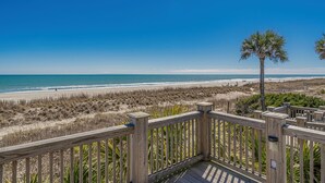 A wooden deck overlooking a beach with a clear sky. - Cottage in Ocean Lakes w/ Gated Porch + Golf Cart (Myrtle Beach)