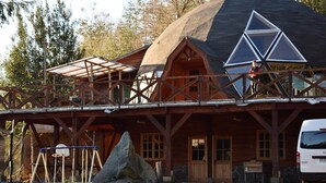 Une cabane en bois dotée d’une grande fenêtre triangulaire et d’un porche abrité.
