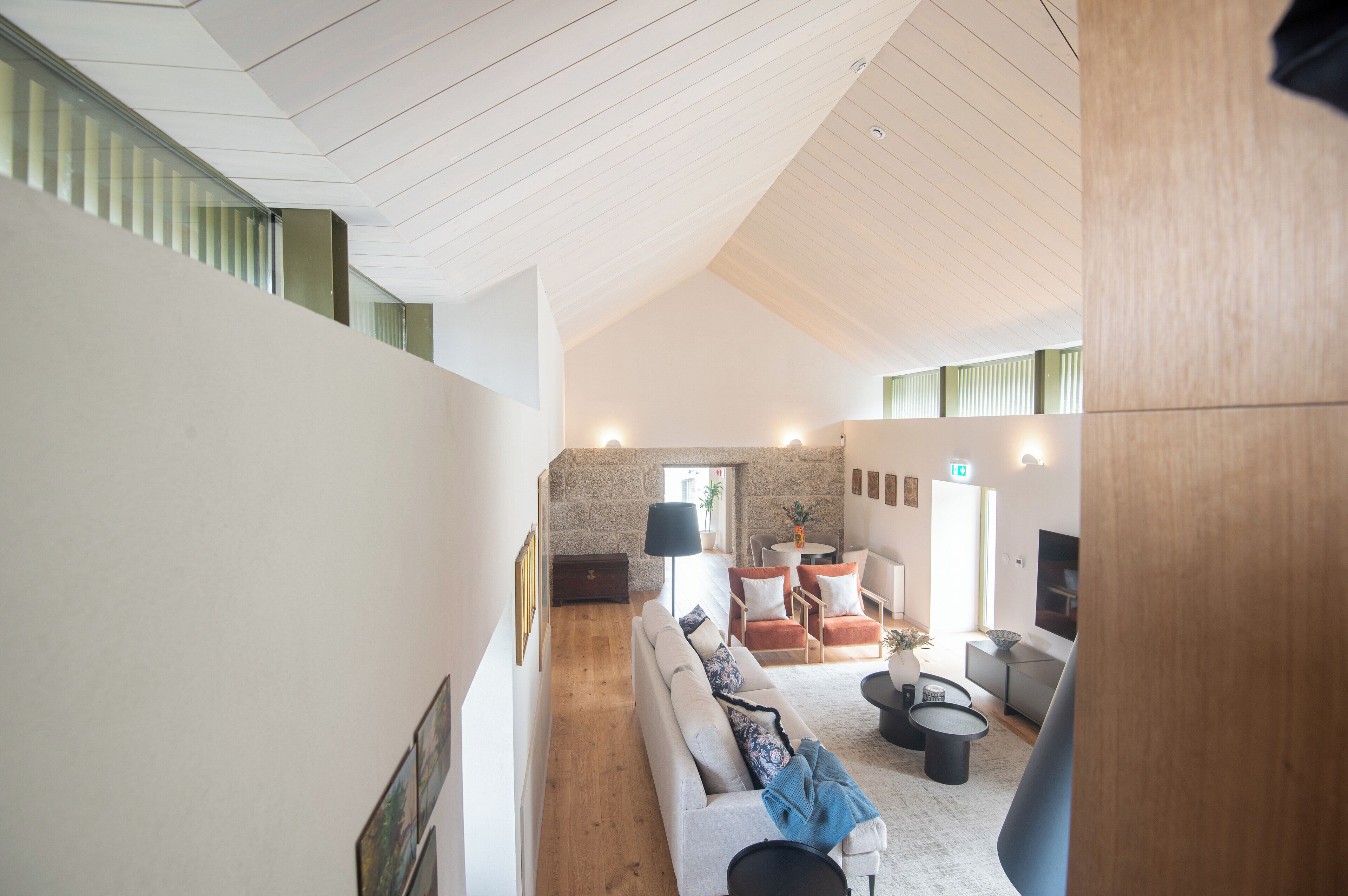 A modern interior with a high ceiling, a sofa set, a coffee table, and a stone wall.