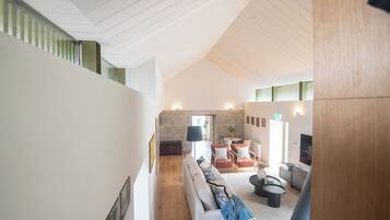 A modern interior with a high ceiling, a sofa set, a coffee table, and a stone wall.