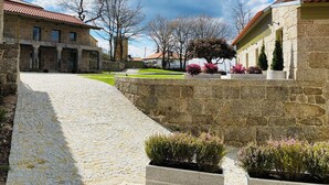 A courtyard with stone buildings, a cobblestone path, and potted plants. - Casa da Fonte de Cima (Celorico de Basto)