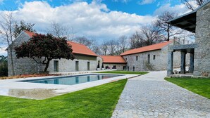 A stone building with a swimming pool, a paved pathway, and a well-maintained lawn. - Casa da Fonte de Cima (Celorico de Basto)