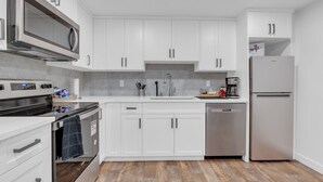 A modern kitchen with white cabinets, stainless steel appliances, and a wooden floor. - Luxury 2Bdr Retreat, Calgary,  Everything You Need, Best coffee (Calgary)