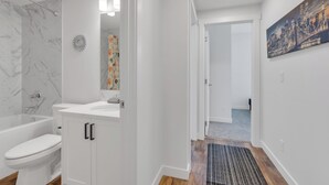 A modern bathroom with a white toilet, a bathtub, and a sink. - Luxury 2Bdr Retreat, Calgary,  Everything You Need, Best coffee (Calgary)