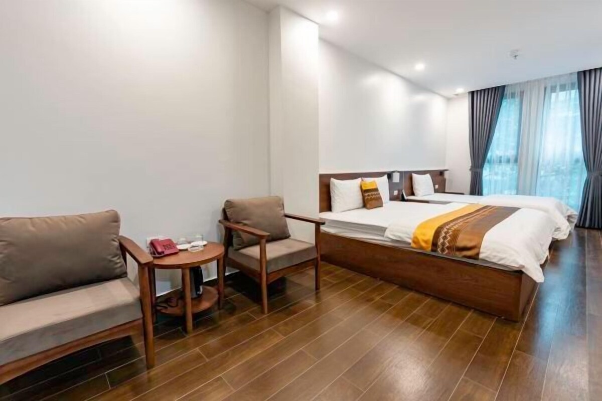 A hotel room with a bed, a sofa, a small table, and a chair.