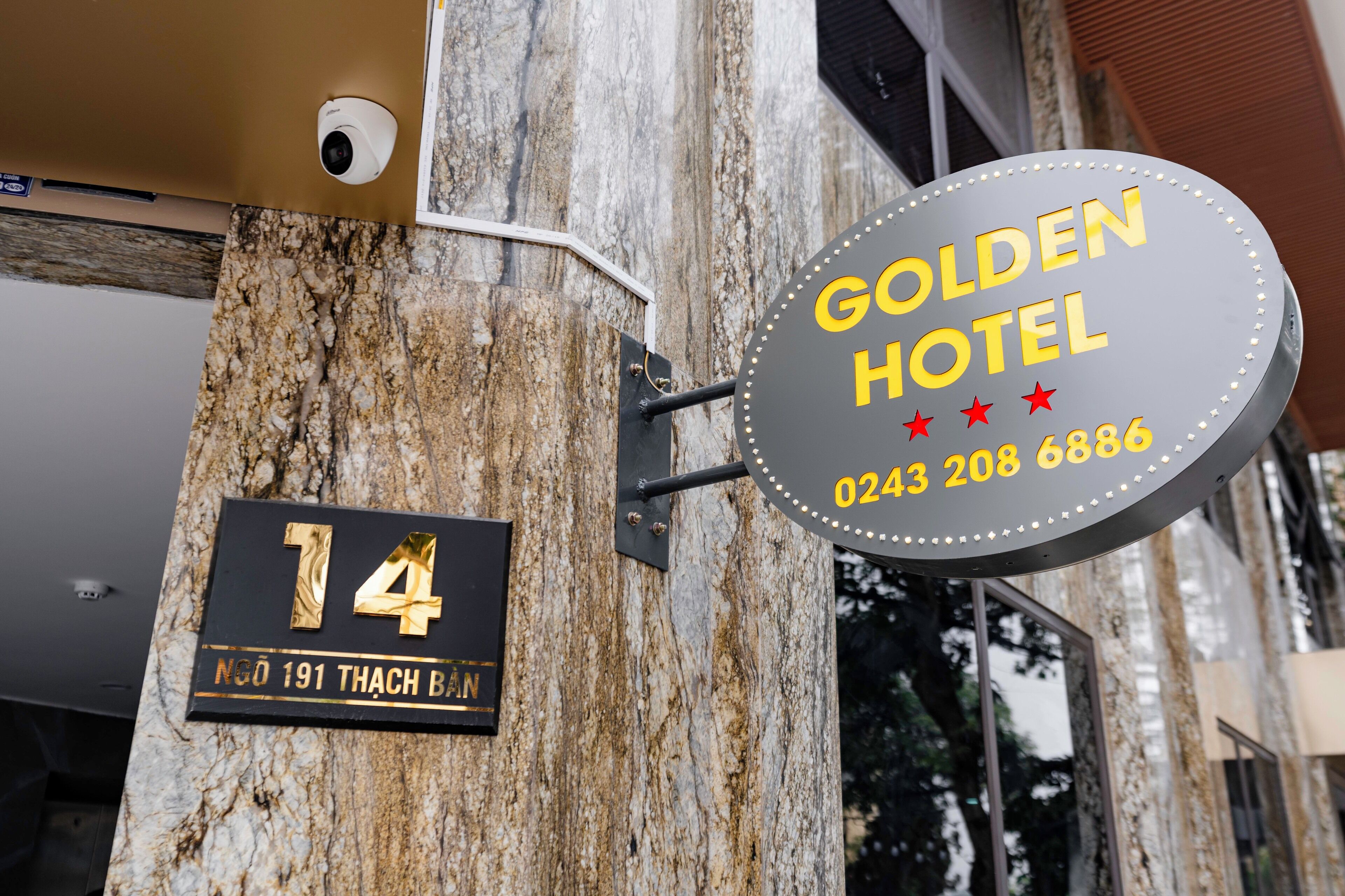 Señal de hotel con el nombre 'GOLDEN HOTEL' y un número de teléfono.