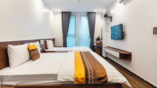 Quarto de hotel com duas camas, televisão de tela plana, ar condicionado e ventoinha.