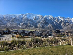 A residential area with houses, a parking lot, and a mountain range in the background. - Loop the Loop (Queenstown)