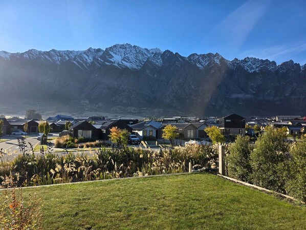 A residential area with houses, a grassy foreground, and snow-capped mountains in the background. - Loop the Loop (Queenstown)