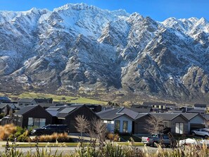 A residential area with modern houses, a parking lot, and a mountainous backdrop. - Loop the Loop (Queenstown)