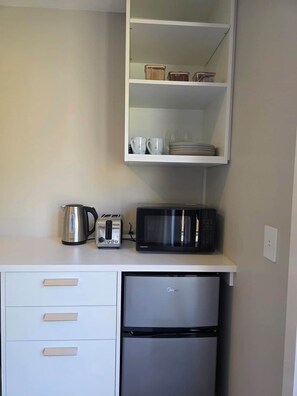 A kitchenette with a microwave, toaster, kettle, and a refrigerator. - Loop the Loop (Queenstown)