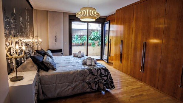 A modern bedroom with a large bed, wooden wardrobe, and a cityscape mural on the wall. - El Refugio, Fuenmayor (Fuenmayor)