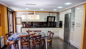 A modern kitchen with a dining area, including a table with chairs, a refrigerator, and a coffee machine. - El Refugio, Fuenmayor (Fuenmayor)