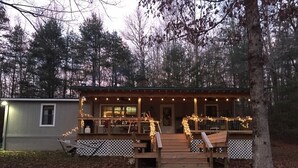 A cabin with a wooden deck, a covered porch, and string lights.