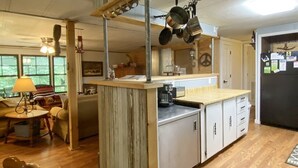 A kitchen with wooden cabinets, a countertop, hanging pots, and a dining area with a table and chairs.