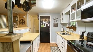 A compact kitchen with wooden cabinets, a black refrigerator, and a stainless steel stove.
